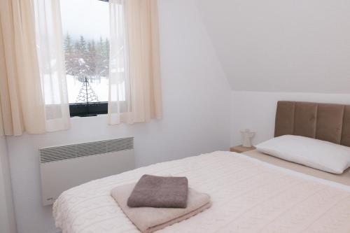 a white bedroom with a bed and a window at De Villa Bey in Kupres