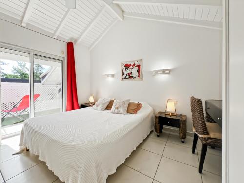 a white bedroom with a bed and a window at Mango Rouge, 2 bedrooms & pool in Saint Martin