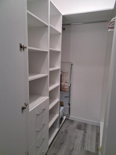 a walk in closet with white shelves and a door at Beti's Apartment in Zambrów