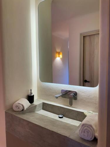 a bathroom with a sink with a large mirror at Chamela Boutique Apartments in Chamela