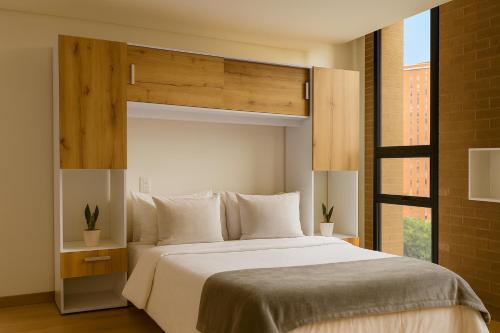 a bedroom with a large white bed and a window at Mitik Vista iluminación y comodida in Bogotá