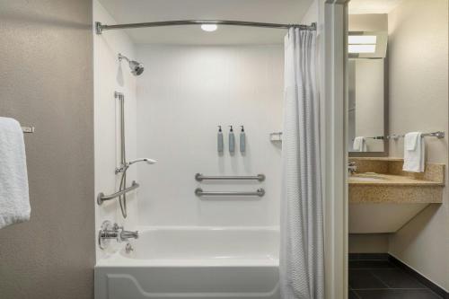 a bathroom with a shower with a tub and a sink at Courtyard by Marriott Charlotte Matthews in Matthews