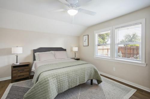 a white bedroom with a bed and two windows at Pet-Friendly Private Cottage In Tahoe Park in Sacramento