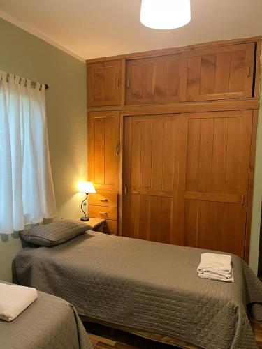 a bedroom with two beds and wooden cabinets at Casa Las Victorias in San Carlos de Bariloche