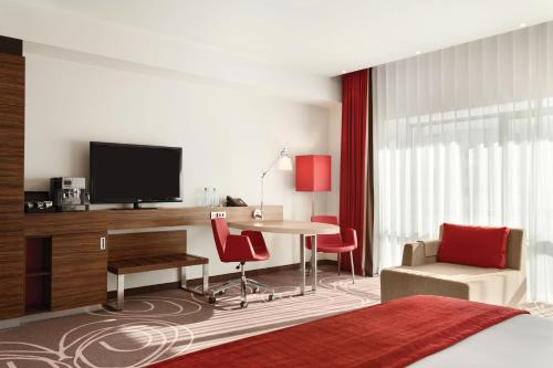 a bedroom with a bed and a desk with a television at Hotel Ramada Pitesti in Piteşti