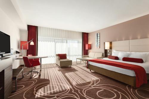 a hotel room with a large bed and a desk at Hotel Ramada Pitesti in Piteşti