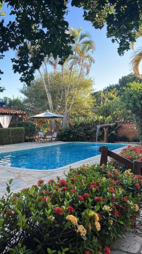 a swimming pool with flowers in a garden at Pousada Casagrande in Pirenópolis