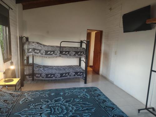 a bedroom with a bunk bed and a flat screen tv at Cabaña Quimey in Villa Rumipal