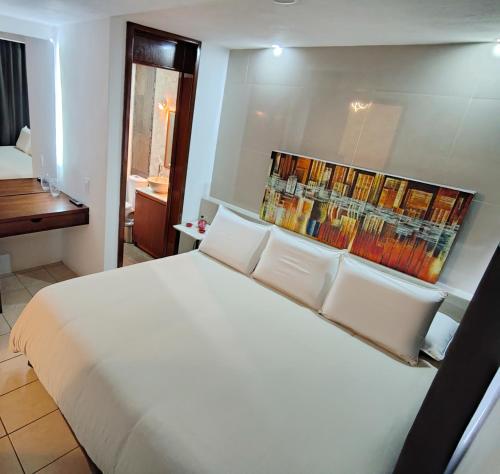 a bedroom with a large white bed with books on the wall at Posada Castillo in Zacatlán