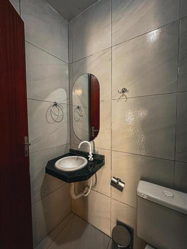 a bathroom with a sink and a mirror and a toilet at Pousada Villa Manzuá in Cascavel