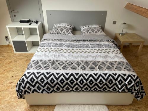 a bedroom with a bed with a black and white comforter at Studio AG in Mellet