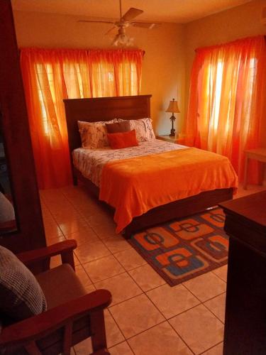 a bedroom with a bed with orange sheets and orange curtains at LRM Home in Basseterre