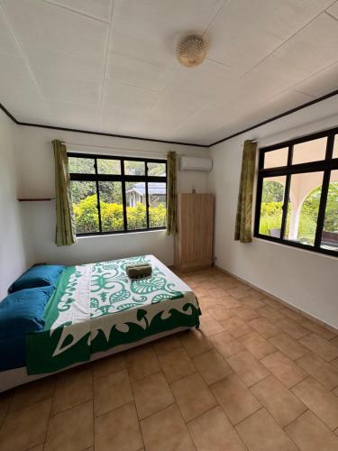 a bedroom with a bed and two windows at TIKI LODGE Hiva oa in Atuona