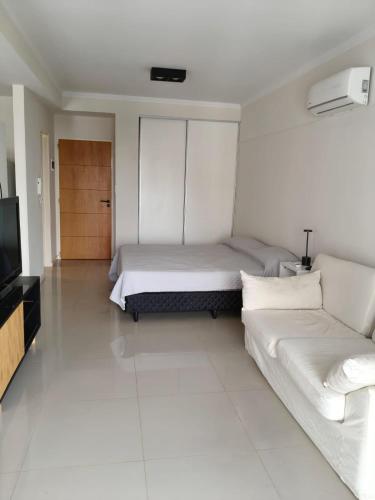 a white bedroom with a bed and a couch at Monoambiente Premium in La Plata