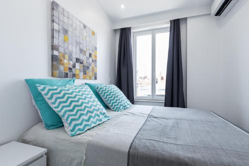 a bedroom with a bed with blue pillows and a window at Olma in Nice