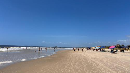 a group of people walking on the beach at Sobrado com Arcondicionado, tomada 220V para veículo elétrico e Wi-Fi em Coroados Guaratuba in Guaratuba
