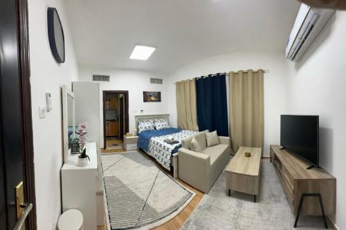 a room with a bed and a couch and a tv at استديو مفروش in Abu Dhabi
