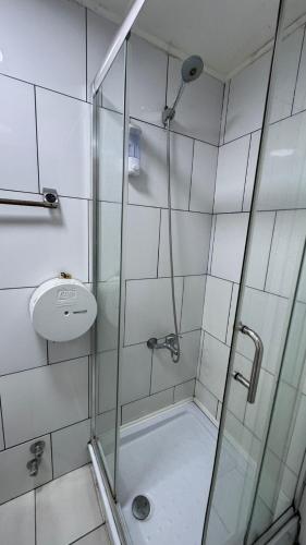 a shower with a glass door and a sink at Aotea Backpacker Hostel in Iquique