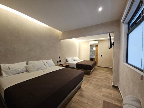 a hotel room with two beds and a window at Hotel Único La Villa in Mexico City