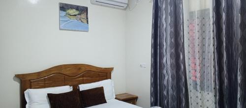 a bedroom with a bed with a wooden headboard and a curtain at Residence Maachaalah in Saint-Louis