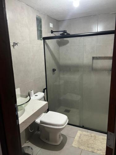 a bathroom with a toilet and a glass shower at Casa Familiar Ampla - Conforto e Lazer no Frances in Praia do Frances