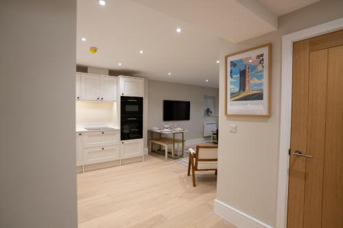 a kitchen with white cabinets and a dining room at Brand New Modern 2-Bed Dog-Friendly Apartment in Broadway High Street - Sleeps 6 in Broadway