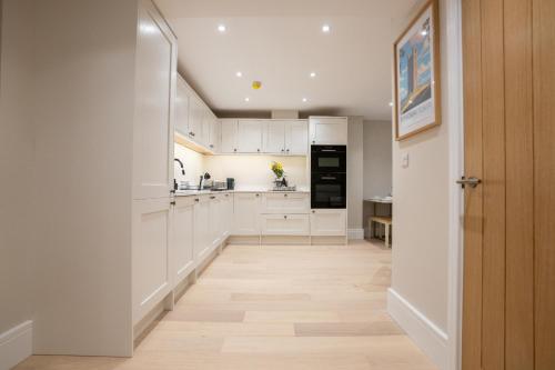 a kitchen with white cabinets and a wooden floor at Brand New Modern 2-Bed Dog-Friendly Apartment in Broadway High Street - Sleeps 6 in Broadway