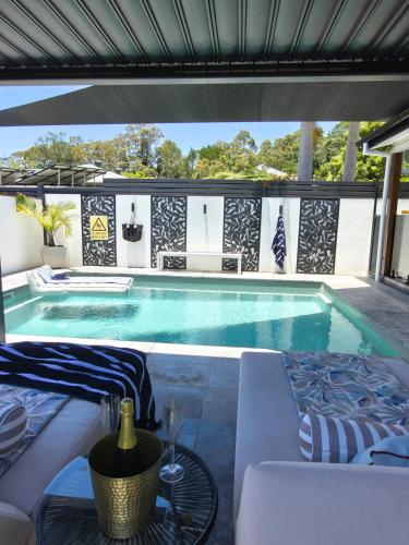 a swimming pool with a table and chairs next to it at Ellie's Holiday Escape - Pool, Romantic, Fireplace in Coffs Harbour