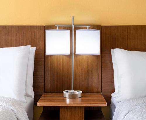 a lamp on a wooden table between two beds at Albuquerque Hotel West by IHG in Albuquerque