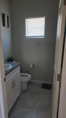 a bathroom with a toilet and a sink and a window at Furnished Private Room in Las Vegas