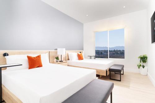 a white room with two beds and a window at Otonomus Hotel Las Vegas in Las Vegas