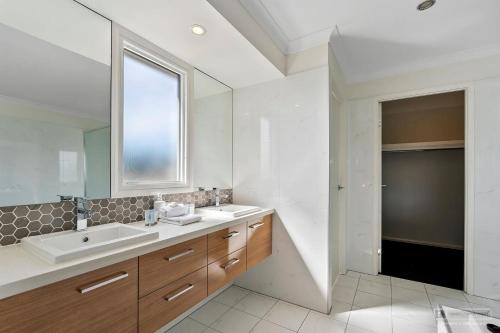 a white bathroom with a sink and a mirror at Maison De Vacances in Banksia Beach