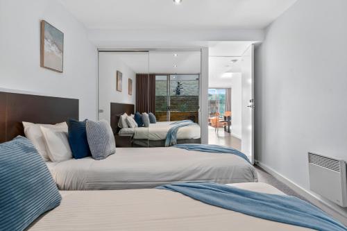 a hotel room with two beds and a mirror at The Dolphin Apartments in Apollo Bay