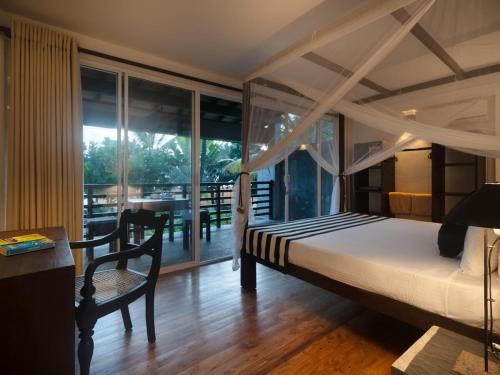 a bedroom with a bed and a balcony with a table at White parrot beach villa in Ambalangoda