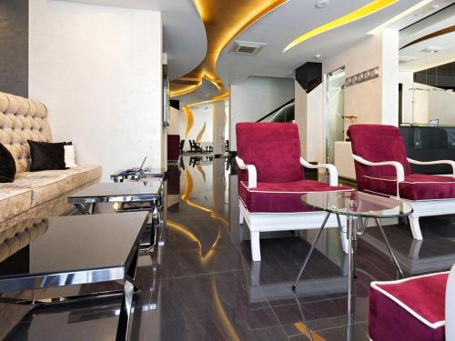 a waiting room with red chairs and tables at Nova City Garni Hotel Signature Collection in Belgrade