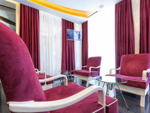 a waiting room with red chairs and a table at Nova City Garni Hotel Signature Collection in Belgrade