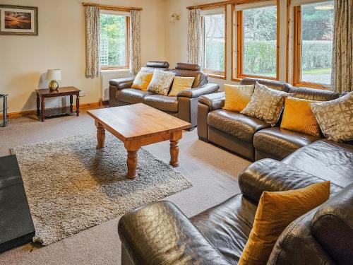 a living room with leather couches and a coffee table at Cotterton Beag in Nethy Bridge
