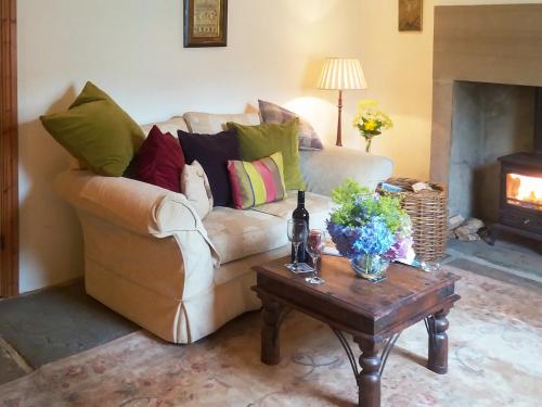 a living room with a couch with pillows and a table at Corner Cottage in Bakewell