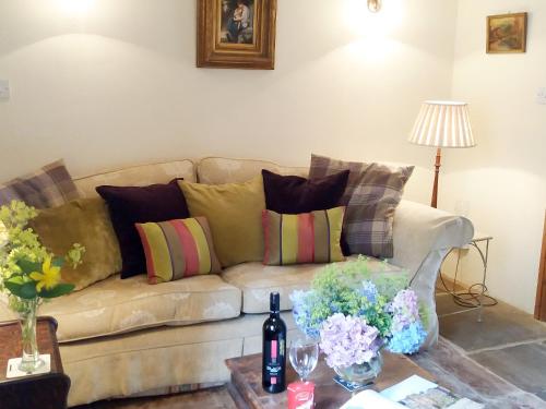 a living room with a couch with pillows and a table at Corner Cottage in Bakewell