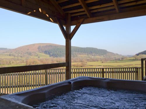 a hot tub on a porch with a view of a mountain at Offa's Dyke Lodge - Uk10835 in Old Radnor