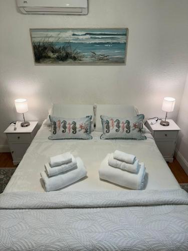 a bed with three pillows on it with two lamps at Mermaid's Lighthouse in West Palm Beach