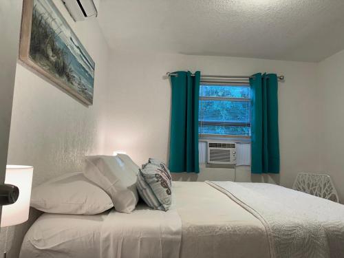 a bedroom with a bed with blue curtains and a window at Mermaid's Lighthouse in West Palm Beach