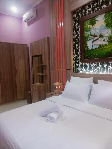 a bedroom with a white bed with a picture on the wall at Umah kampung8 in Mataram