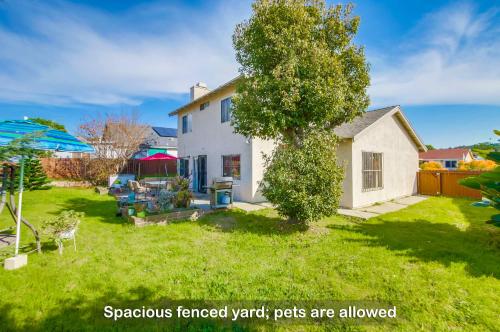 a yard with a white house and a tree at Entire Private Home with 4 Bedrooms - 3 Bathrooms, Big Yard, Garage, King Bed, Crib, Available Now in San Diego
