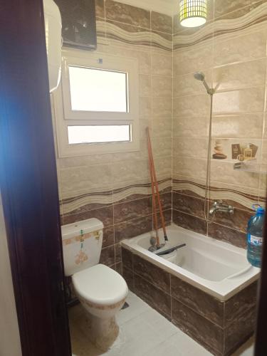 a bathroom with a toilet and a tub and a window at Charming blue see view apartment in Alexandria