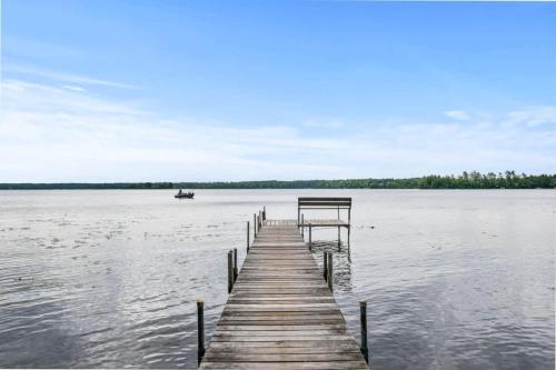 a dock on a lake with a boat in the water at Creekside Big St Germain Lake in Saint Germain
