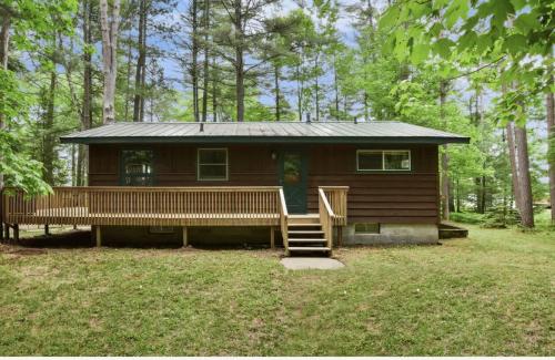 a log cabin in the woods with a porch and stairs at Creekside Big St Germain Lake in Saint Germain