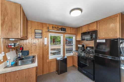 a kitchen with wooden cabinets and a black refrigerator at Loons Landing Legacy in Saint Germain