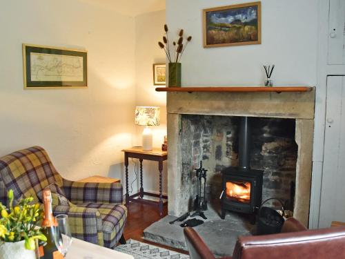 a living room with a fireplace and a couch at Fern Cottage in Bardon Mill