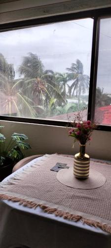 a table with a vase of flowers on a table with a window at MiniSuite con vista al Río in Boca del Río